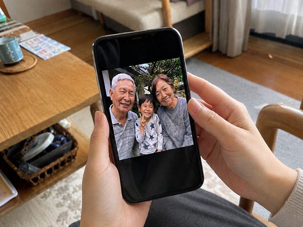 スマホを手に取って写真を見ている光景